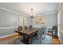 Formal dining room features a modern chandelier, gray chairs, and wainscoting at 9605 Mountain Ivy Ct, Charlotte, NC 28210