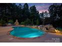 A backyard oasis featuring a sparkling pool and stone fireplace offers luxury and relaxation at 146 Bullfinch Rd, Mooresville, NC 28117