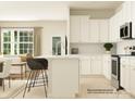 Bright kitchen with white cabinets, stainless steel appliances, and a sleek island with counter seating at 233 Runner Stone Ln, Fort Mill, SC 29715