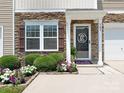 Close up of home's entrance with lovely rock facade, decorative door, manicured shrubs, and beautiful flowers at 342 Battery Cir, Clover, SC 29710