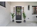 An elegant front door with glass and wreath, flanked by plants and sidelights, with modern exterior lighting at 4209 Windwood Cir, Charlotte, NC 28226