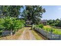 A long driveway leads to a secluded home, framed by lush greenery and a charming white picket fence at 6314 Providence Church Rd, Vale, NC 28168