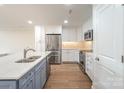 Modern kitchen with stainless steel appliances, white cabinets, gray island, and hardwood floors at 633 Portside Dr, Davidson, NC 28036