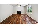 Open living room area with a fireplace, hardwood floors and natural light from a window at 8701 Holly Creek Ct, Charlotte, NC 28216