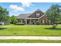 Inviting brick home with a green lawn, covered porch and decorative shutters at 1006 Spring Rose Ln, Matthews, NC 28104