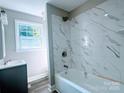 Bathroom featuring modern vanity and tub with white marble tile and rainfall shower head at 509 8Th Avenue Ext, Cramerton, NC 28032