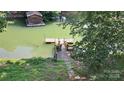 The backyard dock overlooks the serene green lake with a wooden house at 729 Victoria Ln, Hickory, NC 28601