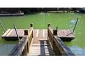 A close-up of the wooden dock overlooking a green lake with a wooden house at 729 Victoria Ln, Hickory, NC 28601
