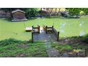 Private backyard dock sitting on a green lake with a small wooden house on the other side at 729 Victoria Ln, Hickory, NC 28601