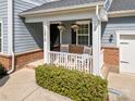 Cozy front porch with white railing, brick accents, and hanging flower baskets that create a welcoming entrance at 12415 Es Draper Dr, Huntersville, NC 28078