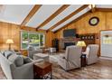 Inviting living room with wood paneled walls, vaulted ceiling, brick fireplace, and cozy furnishings at 143 Bostian Lake Rd, Statesville, NC 28677