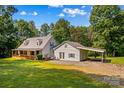 Well-maintained home boasts a wraparound porch, metal roof, an attached carport, and a tree-lined yard at 265 River Run Rd, Statesville, NC 28625