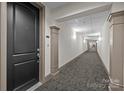 Long interior hallway with carpet and neutral walls leading to a door on the left at 4625 Piedmont Row Dr, Charlotte, NC 28210