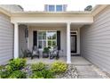 Inviting front porch with rocking chairs, decorative plants, and a stylish front door with glass detailing at 5129 Devonshire Rd, Denver, NC 28037