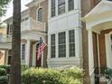 Brick townhouse featuring a charming balcony, covered porch, an American flag, and manicured landscaping at 570 Sixth Baxter Xing # 16, Fort Mill, SC 29708