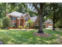 A beautiful brick home is surrounded by lush greenery, a well-manicured lawn, and mature trees at 6612 Saunton Ct, Charlotte, NC 28277