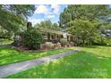Brick home features a well manicured lawn, mature trees, and walkway to a covered porch at 1104 Pump Station Rd, Kannapolis, NC 28081
