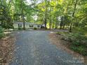 Gravel driveway leading to a single story home secluded in the woods with covered parking area at 16711 Indian Mound Rd, Albemarle, NC 28001