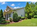 View of a home's side exterior showcasing manicured landscaping, vinyl siding, and lush green lawn at 8712 Soaring Eagle Ln, Waxhaw, NC 28173