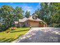 Charming brick home with a spacious driveway and two-car garage nestled among trees at 107 Creekwood Dr, Dallas, NC 28034