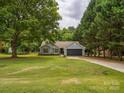 Landscaped single story home with mature trees, a two-car garage, and a well manicured lawn at 1109 Manchester Ln, Charlotte, NC 28227