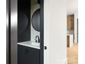 Stylish powder room with a modern vanity, round mirror and sleek black fixtures at 1511 Waverly Ave, Charlotte, NC 28203