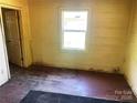 A bright bedroom featuring a window, worn wood floors, and a glimpse into an adjacent room at 213 Maple St, Rock Hill, SC 29730