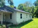 Side view of a home with weathered siding, windows, and a backdrop of trees against a blue sky at 213 Maple St, Rock Hill, SC 29730