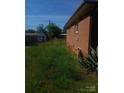 Backyard featuring a brick home exterior, chain link fence and overgrown green grass at 2815 Highland Dr, Lincolnton, NC 28092