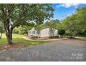 A lovely home featuring a side yard and driveway with a canopy of mature trees at 329 W Red Cross Rd, Oakboro, NC 28129