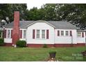 Rear exterior featuring a brick chimney, white siding, and well maintained landscaping at 4143 E Maiden Rd, Maiden, NC 28650