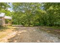 Large backyard area with gravel, trees, and a covered porch, offering ample space for parking and outdoor activities at 4699 Cherrystone Rd, Lancaster, SC 29720