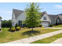Well-maintained house features a green lawn, mature tree, and a two-car garage, showcasing suburban living at 6907 Hunts Mesa Dr, Fort Mill, SC 29707