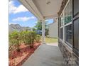 A view from the front porch featuring shrubbery and wood mulch and a house in the distance at 1307 Farm Branch Sw Dr, Concord, NC 28027
