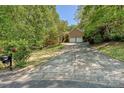 Long driveway leading to a brick home with a two-car garage surrounded by lush greenery and mature trees at 9600 Lockhorn Ct, Mint Hill, NC 28227