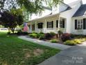 View of home with a sidewalk leading to the front porch featuring an American flag and manicured landscaping at 135 Primrose Dr, Salisbury, NC 28147