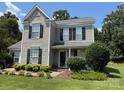 Charming two-story home with gray siding, black shutters and well-maintained landscaping at 148 W Walnut Ave, Mount Holly, NC 28120