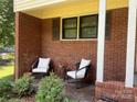 Cozy front porch with brick flooring, decorative chairs, and lush landscaping at 1909 Normandy Rd, Kannapolis, NC 28081