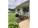Inviting front porch with white railings, flower baskets, and manicured landscaping at 3810 Spike Ln, Vale, NC 28168