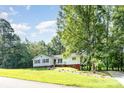 Inviting one-story home with a lush front lawn, pathway and mature trees at 7154 Woodcock Trl, Stanley, NC 28164