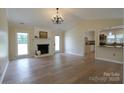 Bright living room with hardwood floors, a fireplace, a chandelier and an open view into kitchen at 8829 Gelligum Dr, Charlotte, NC 28277