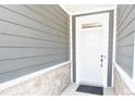 Inviting front entrance with gray siding accented by stone, leading to a bright white door at 12209 Riceland Way, Midland, NC 28107