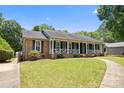 Inviting exterior of a brick home with a covered front porch, complemented by lush green landscaping and a curved walkway at 5006 Crooked Oak Ln, Charlotte, NC 28226