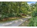 The gravel driveway stretches back to the house surrounded by green trees and mature landscaping at 5212 Timber Creek Ct, Kings Mountain, NC 28086