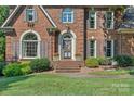 Close up of the brick front of this home, showing the front door and surrounding landscaping at 10500 Kilmory Ter, Charlotte, NC 28210