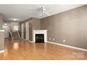Spacious living room with hardwood floors, fireplace, ceiling fan, and staircase at 10613 Prairie Ridge Ln, Charlotte, NC 28213