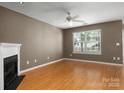Living room featuring hardwood floors, fireplace, ceiling fan, and natural light from the window at 10613 Prairie Ridge Ln, Charlotte, NC 28213