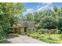 A charming house with a gabled roof, garden, and a covered carport surrounded by lush trees at 4124 Oakwood Rd, Charlotte, NC 28269
