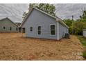 Back exterior showcasing light blue siding, windows, and an AC unit, set in newly seeded yard at 651 S Elm St # 2, Statesville, NC 28677