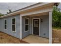 Inviting front porch featuring gray siding, white trim, and a black front door, ready for personalization at 651 S Elm St # 2, Statesville, NC 28677